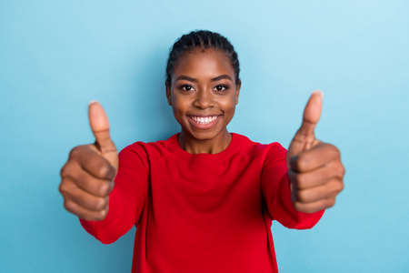 Photo of sweet young braids hairdo lady thumb up camera wear red pullover isolated on blue color backgroundの写真素材