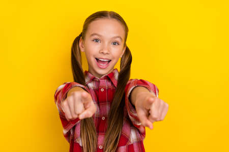 Photo of pretty excited schoolkid dressed plaid shirt pointing fingers you isolated yellow color...