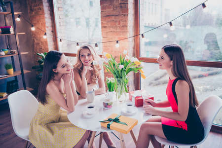 Photo of three attractive girls sit in comfort coffee shop enjoy celebrate festive event discussing newsの写真素材