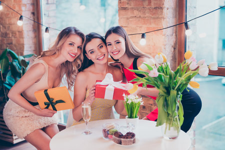 Classy three ladies fellows enjoy festive birthday celebration hold wish dream package sit table in cafe wear dressの写真素材