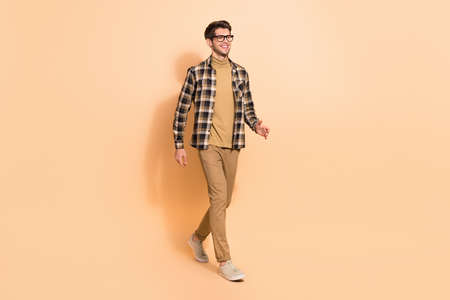 Full length body size view of attractive cheerful guy agent broker expert walking isolated over beige pastel color backgroundの写真素材