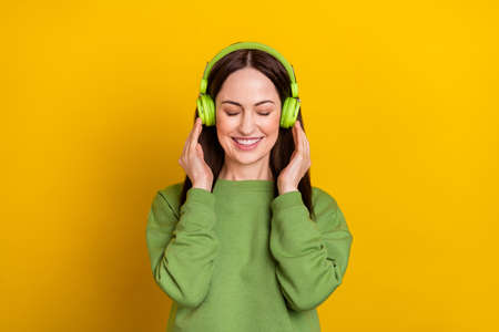 Portrait of attractive dreamy cheerful woman listening radio hit single isolated over bright yellow color backgroundの写真素材
