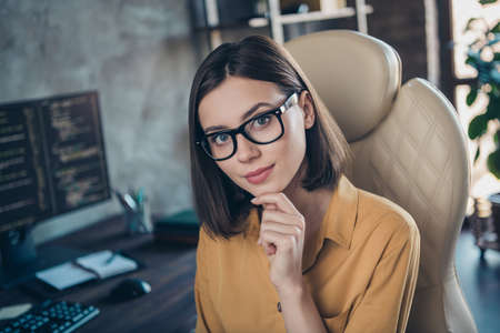 Portrait of attractive girl providing outsource service network tech support touching chin at workplace workstation indoorsの写真素材