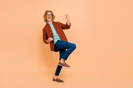 Full length body size view of attractive cheerful lucky red-haired guy dancing having fun isolated over beige pastel color backgroundの写真素材