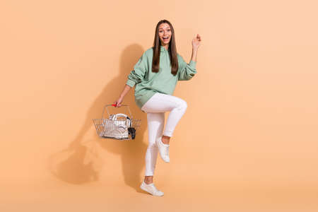Full length body size view of attractive cheerful girl holding devices goods dancing isolated over...