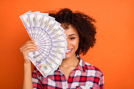 Photo of pretty wavy lady hold money close face wear red shirt isolated on orange background