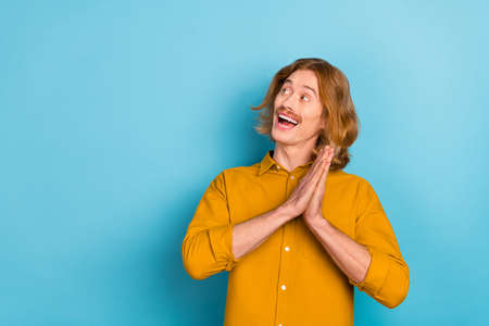 Portrait of attractive cheerful minded long-haired guy looking aside copy space ad isolated over...