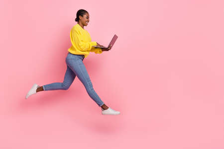 Full size profile side photo of young lady chat type laptop walk manager jumper isolated over pink...