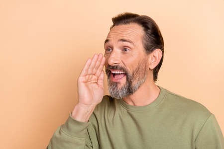 Portrait of attractive cheerful amazed man saying good news advert ad isolated over beige pastel color backgroundの写真素材