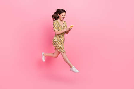 Photo of shiny impressed lady dressed print outfit jumping high chatting modern device empty space...