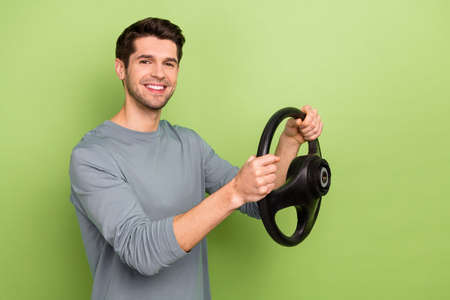 Profile photo of funky young brunet guy drive car wear grey pullover isolated on green color...