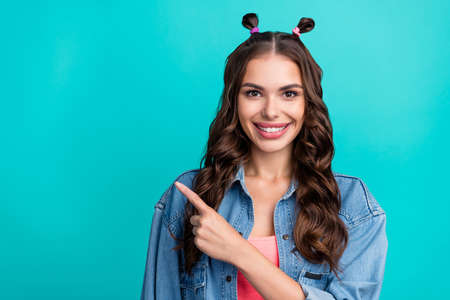 Photo of young cheerful girl indicate finger empty space recommend suggest banner isolated over turquoise color backgroundの写真素材