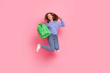 Full body photo of blond teenager girl jump wear bag sweater jeans sneakers isolated on pink backgroundの写真素材