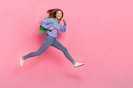 Full size photo of blond small girl run wear bag sweater jeans shoes isolated on pink background