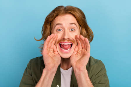 Portrait of attractive funky cheerful guy saying good news ad promo isolated over pastel blue color backgroundの写真素材