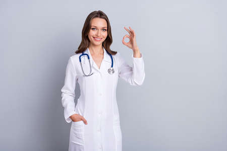 Photo of qualified lady paramedic suggest covid prevent vaccine show okay symbol isolated grey color backgroundの写真素材