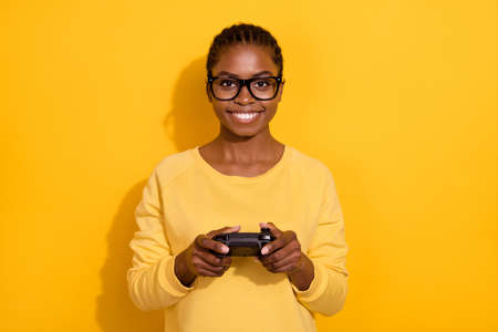 Portrait of attractive cheerful girl playing video game spending spare time isolated over bright yellow color backgroundの写真素材