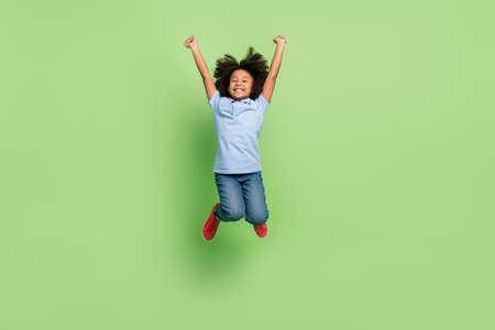 Full length body size view of beautiful cheerful pre-teen girl jumping having fun isolated over green color backgroundの写真素材