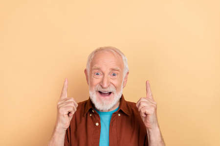 Photo of hooray aged grey hairdo man index up wear brown outfit isolated on beige color backgroundの写真素材