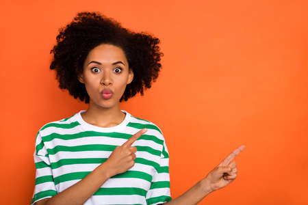 Portrait of attractive amazed funny wavy-haired girl showing copy empty space ad wow isolated over bright orange color backgroundの写真素材