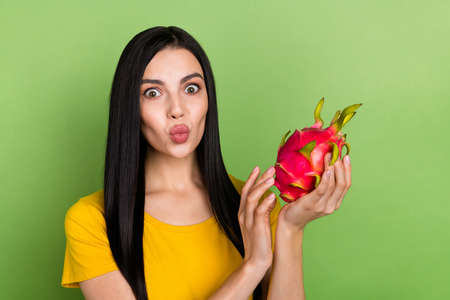 Photo of funny funky lady dressed yellow t-shirt holding exotic fruit lips pouted isolated green color backgroundの写真素材