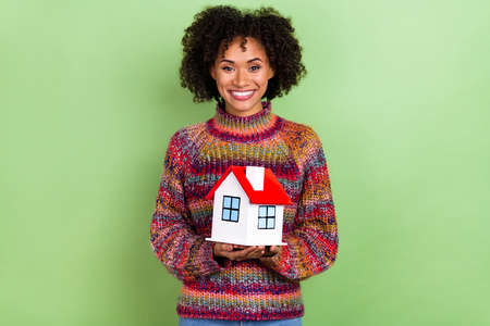 Photo of hooray millennial curly hairstyle lady hold house wear red sweater isolated on green color backgroundの写真素材
