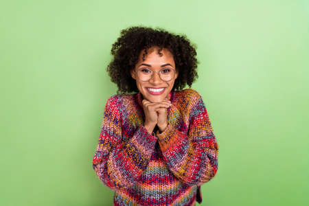 Portrait of excited positive lady hands under chin beaming smile isolated on green color background