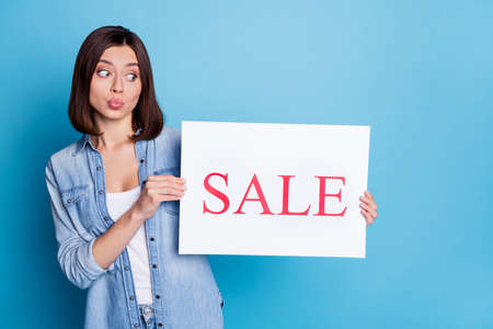 Photo of pretty young lady kiss lips look arms hold paper sale card isolated on blue color...