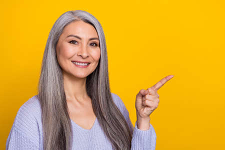 Photo of young cute grandma promote recommend you eshop shopping season coupons isolated on yellow...