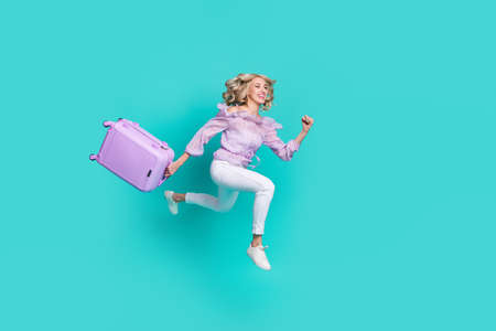 Photo of charming pretty lady wear violet blouse running check in holding baggage isolated turquoise color backgroundの写真素材