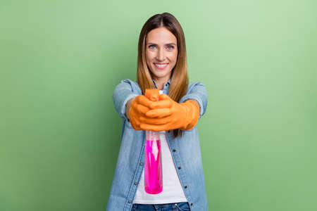 Photo of mature brown hairdo lady clean you wear jeans shirt gloves isolated on green color backgroundの写真素材
