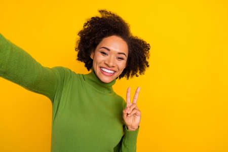 Photo of young lovely lady show fingers peace hello v-symbol make selfie isolated over yellow color...