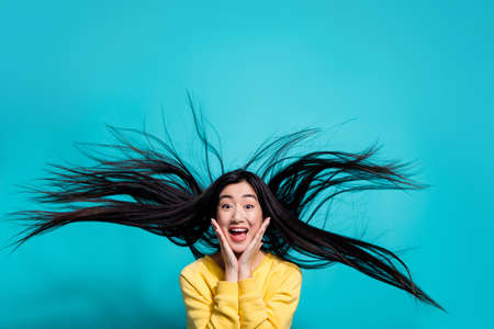 Photo of charming impressed lady dressed yellow sweater arms cheeks wind blowing isolated turquoise color backgroundの写真素材