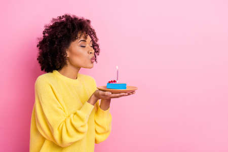 Profile side photo of young girl blow candle dream yummy sweet dessert isolated over pink color backgroundの写真素材