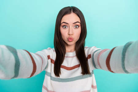 Photo of funky charming lady dressed striped pullover recording self video sending you kiss isolated teal color backgroundの写真素材