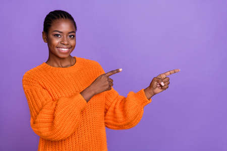 Photo of young lovely girl indicate fingers empty space promotion proposition suggest isolated over purple color backgroundの写真素材