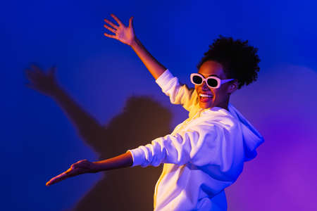 Photo of pretty excited lady dressed hoodie dark eyewear holding arms empty space isolated purple color backgroundの写真素材