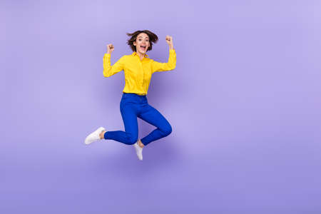 Full length photo of sweet millennial brunette lady jump yell wear shirt pants footwear isolated on purple backgroundの写真素材