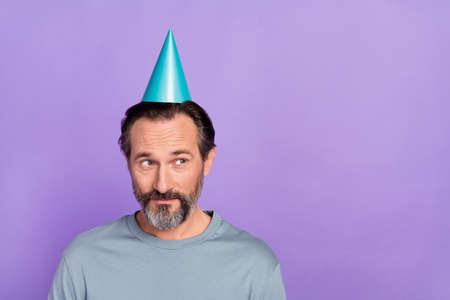 Photo of mature man wear paper headwear wonder guess look empty space isolated over violet color...