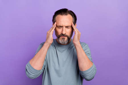 Portrait of unsatisfied sick ill person closed eyes arms on temples isolated on violet color...