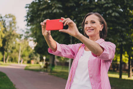 Portrait of cheerful nice person hold telephone take selfie photo good mood spend pastime park...