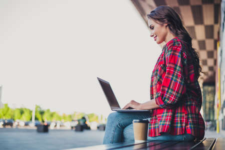 Profile side view portrait of attractive skilled focused girl using laptop writing email spending sunny day outdoorsの写真素材