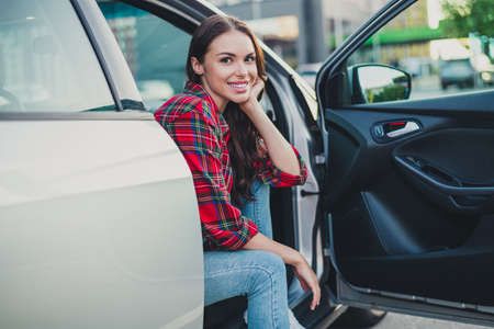 Portrait of attractive cheerful wavy-haired girl passenger sitting in auto spending time vacation weekend on parking outdoorsの写真素材