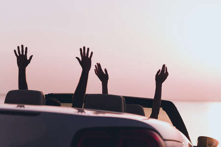 Photo of carefree excited boyfriend girlfriend rising arms going honeymoon driving cabriolet outdoors countrysideの写真素材