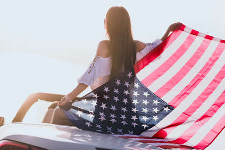Photo of sweet adorable girl wear casual clothes riding cabriolet holding american flag countrysideの写真素材