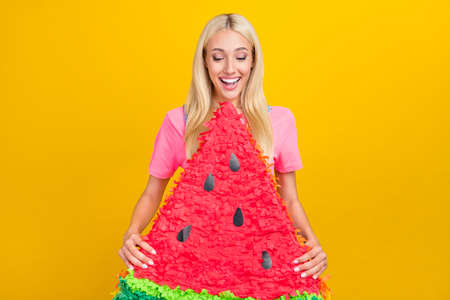 Portrait of attractive cheerful girl holding water melon biting fooling isolated over bright yellow color backgroundの写真素材