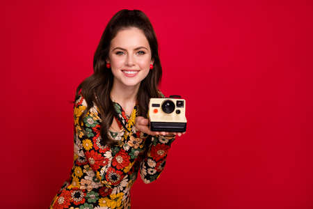 Portrait of attractive cheerful girl holding old fashioned cam making capture cadre isolated over bright red color backgroundの写真素材