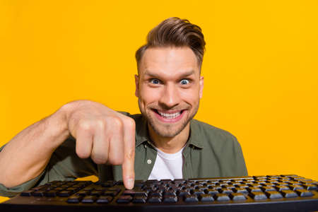 Portrait of attractive cheerful crazy guy pressing button studying gambling having fun isolated over...