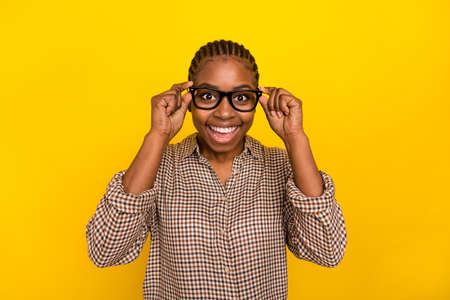 Photo of excited adorable lady dressed checkered shirt arms spectacles smiling isolated yellow color backgroundの写真素材