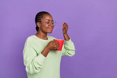 Photo of young dreamy adorable woman enjoy smell of hot chocolate coffee with closed eyes isolated on violet color backgroundの写真素材